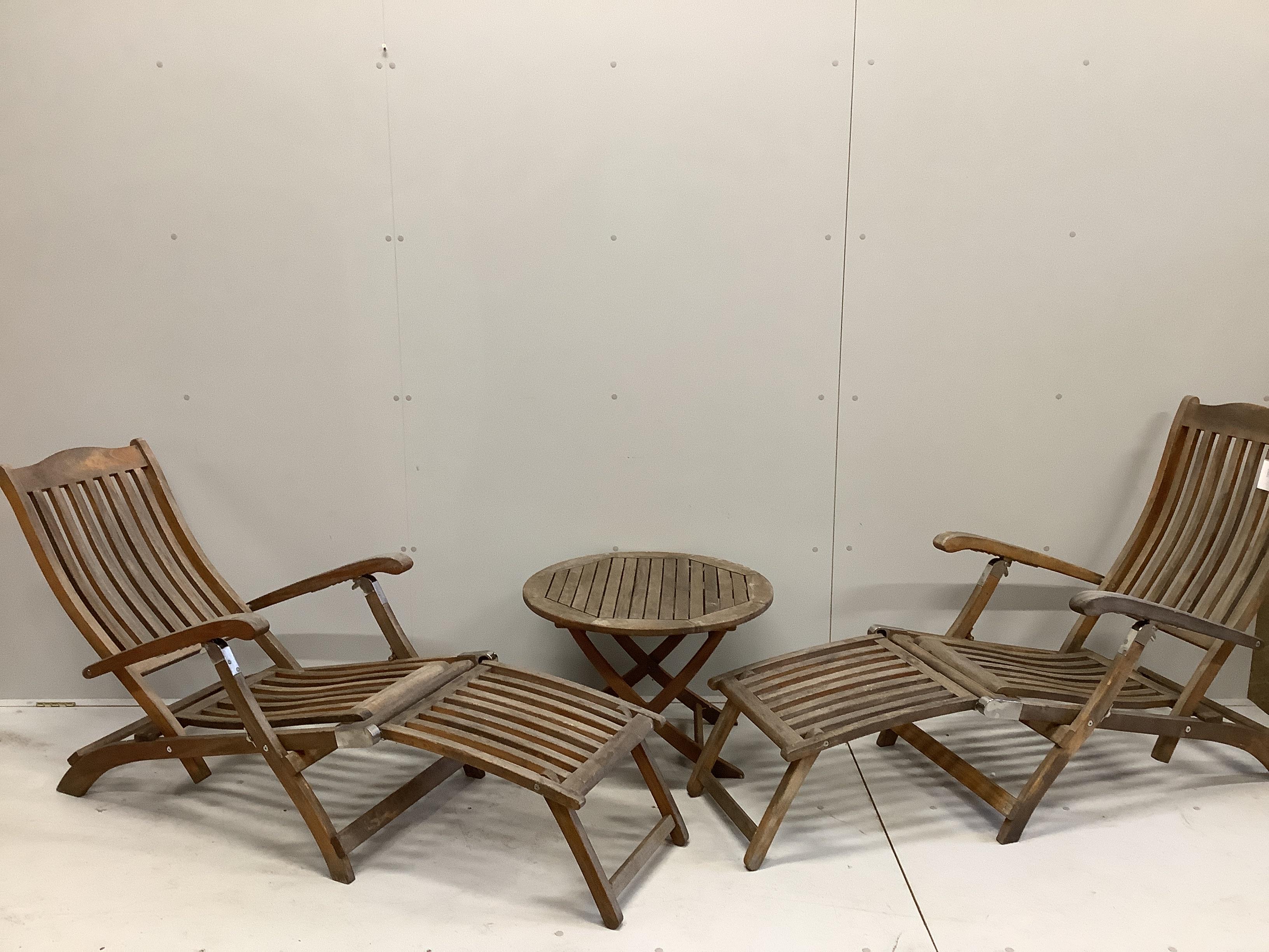 A pair of Alexander Rose weathered teak steamer chairs and a circular teak garden table